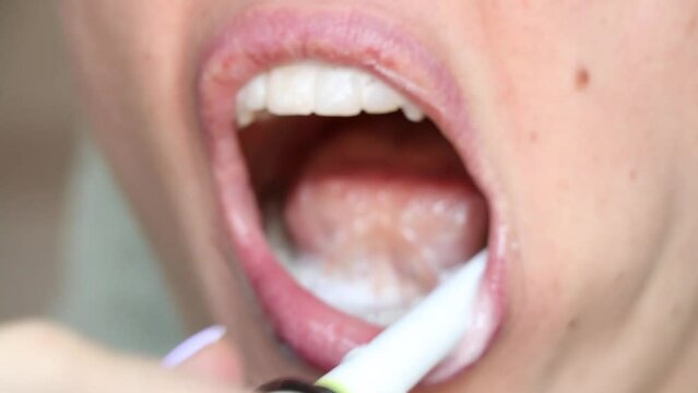 Girl brushing her teeth with an electric toothbrush close-up, dental care, no retouching