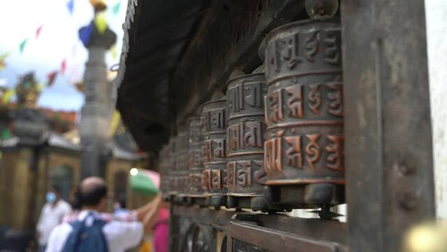 People spinning religious prayer wheels with written mantra Om Mani Padme Hum. Kathmandu, Nepal.