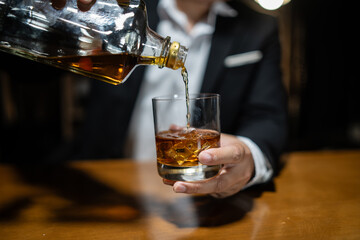 Bartender pours whiskey to customer in tavern