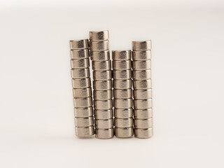 stacks of individual Neodynium silver strong magnets isolated on a white background hundreds of...