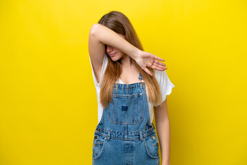 Young caucasian woman isolated on yellow background covering eyes by hands