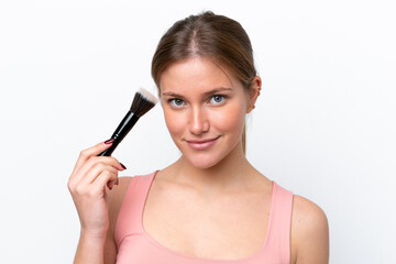 Obraz premium Young caucasian woman isolated on white background holding makeup brush