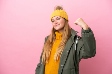 Young blonde woman wearing winter jacket isolated on pink background doing strong gesture