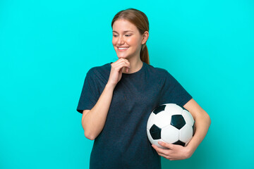 Young football player woman isolated on blue background looking to the side and smiling
