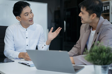 Two Young Asian businessman discuss with new startup project Idea presentation, analyze planning and financial statistics and investment market at office.