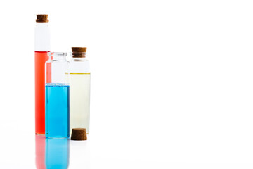 Three glass bottles filled colorful liquids with cork on a isolated white background