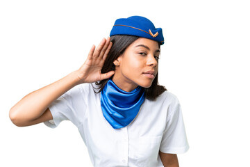 Airplane stewardess African american woman over isolated background listening to something by...