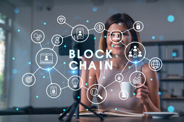 Happy woman is making video blog using smartphone on a tripod explaining with hands at office workplace. Concept of online stream, business education, conference call. Blockchain hologram