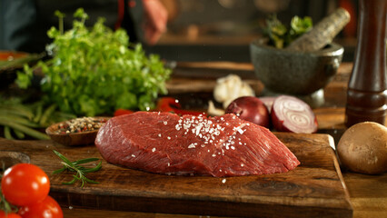 A view of a fresh raw beef steak on a wooden board placed on the kitchen counter. The concept of...
