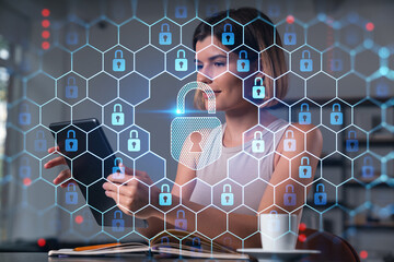 Smiling businesswoman in casual wear holding tablet device touching it at office workplace. Concept of distant work, business education, information technology. Lock icons hologram