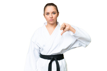 Young blonde woman doing karate over isolated chroma key background showing thumb down with...