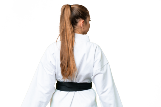 Young blonde woman over isolated chroma key background doing karate in back position