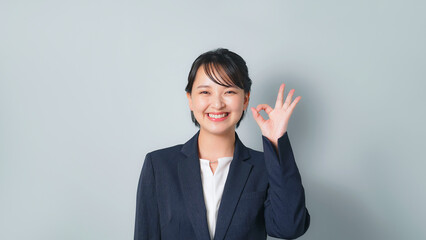 OKサインを見せるビジネススーツを着た女性