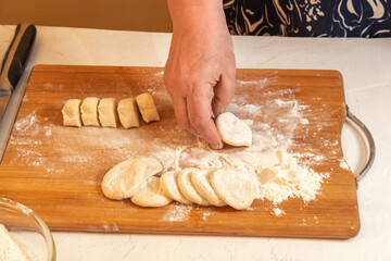 The cook rolls pieces of dough in flour to roll them into thin flat cakes.