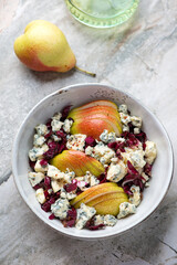 Bowl of salad with radicchio, pear and blue cheese, vertical shot on a grey granite background, high angle view
