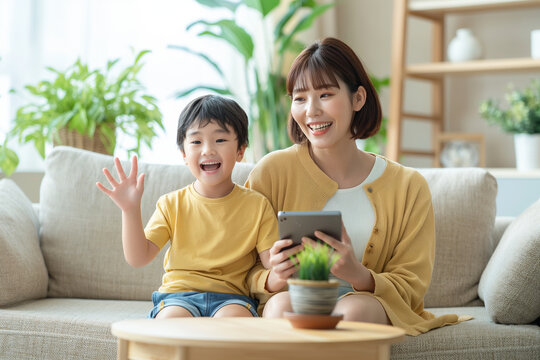 Asian mother sits on the sofa, holding an iPad and talking to her son who is sitting in front of her with his hands raised. The child wears shorts and yellow short sleeves. Generative Ai Illustration.