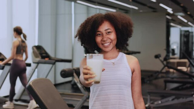 African American woman finishing workout and drinking protein milk shake vitamins after training. Bodybuilding. Healthy Friend lifestyle.