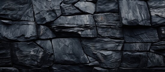A monochromatic image featuring a detailed black granite rock wall, showcasing the natural textures and patterns of the stone surface.