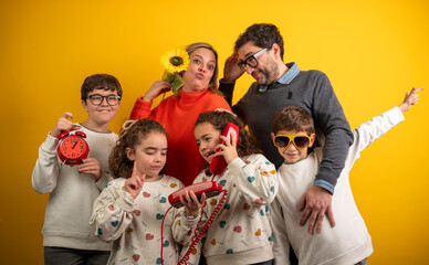 Joyful family with three children engaged in playful activities against a yellow background.