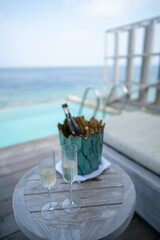 A champagne bottle on bucket filled with ice on with tropical ocean background.
