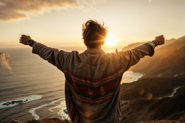 Handsome young man with arms outstretched enjoying sunset on mountain top