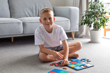 A boy is playing a logical wooden game on the carpet. Montessori educational toys, geometric puzzle