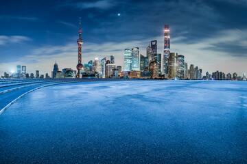 Asphalt road and modern city commercial buildings at night in Shanghai. Famous financial district landmark in Shanghai.