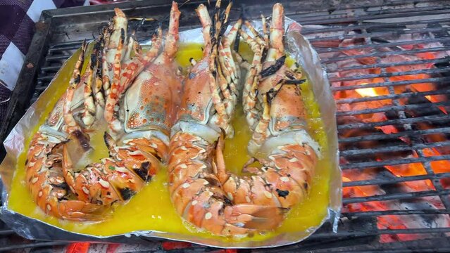 Lobster with flavored butter. Herb butter, lemon. Delicious healthy traditional food closeup served for lunch Giant grilled lobster cook on charcoal stove at Thai street food night market.