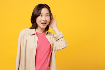 Young curious nosy woman of Asian ethnicity wear pink t-shirt beige shirt pastel casual clothes try...