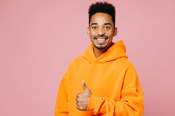 Side view young man of African American ethnicity he wear yellow hoody casual clothes showing thumb up like gesture isolated on plain pastel light pink background studio portrait. Lifestyle concept.