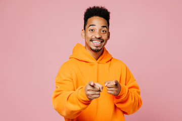 Young man of African American ethnicity wear yellow hoody casual clothes point index finger camera on you motivating encourage isolated on plain pastel light pink background studio. Lifestyle concept.
