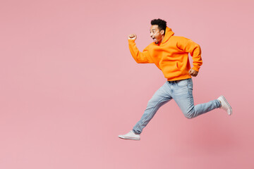 Fototapeta na wymiar Full body side profile view fun young man of African American ethnicity he wear yellow hoody casual clothes jump high run fact isolated on plain pastel light pink background studio. Lifestyle concept.