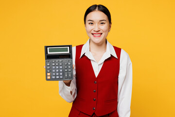 Young corporate lawyer employee business woman of Asian ethnicity wear formal red vest shirt work at office hold use blank screen calculator isolated on plain yellow background studio. Career concept.