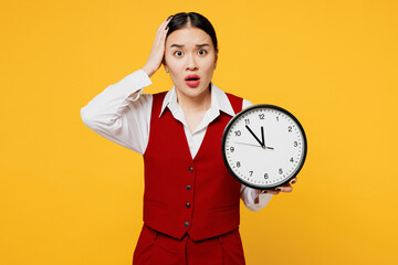 Young sad shocked upset corporate lawyer employee business woman of Asian ethnicity wear formal red vest shirt work at office hold head clock isolated on plain yellow background studio Career concept