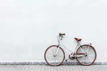 Poster Vélo White vintage bicycle with brown leather saddle leaning against a white wall on a tiled sidewalk