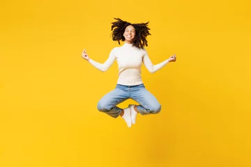  Full body little kid teen girl wear white casual clothes jump high hold spreading hands in yoga om aum gesture relax meditate try to calm down isolated on plain yellow background. Childhood concept. © ViDi Studio