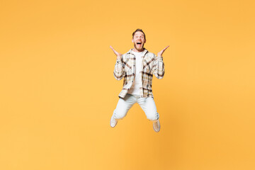 Full body overjoyed exultant young Caucasian man wear brown shirt casual clothes jump high spread hands scream look camera isolated on plain yellow orange background studio portrait Lifestyle concept