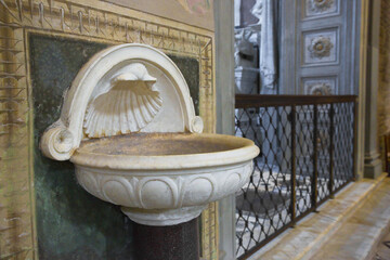 Inlaid marble holy water font and ancient romanesque church - Powered by Adobe