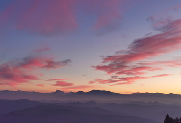 Fototapeta na wymiar Nuvole rosse nel cielo sopra le montagne nel tramonto dorato