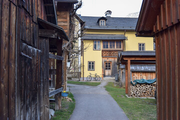 Fototapeta premium Callejuela rural con casas de madera a los lados y una casa amarilla al fondo con una bicicleta