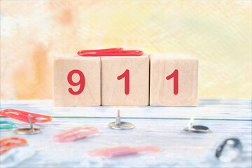 The number 911 assembled from wooden cubes on a colored background