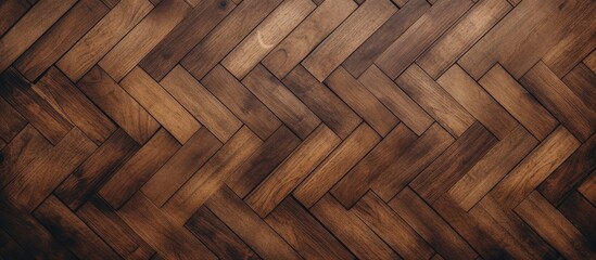 A brown old wooden parquet floor featuring a chevron pattern, creating a stylish and intricate design. The pattern consists of V-shaped planks arranged in a zigzag formation.
