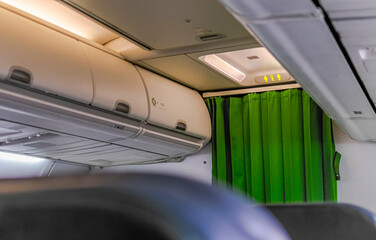 Interior view of a first-class seat aircraft, a green curtain separating the entrance aisle and the...