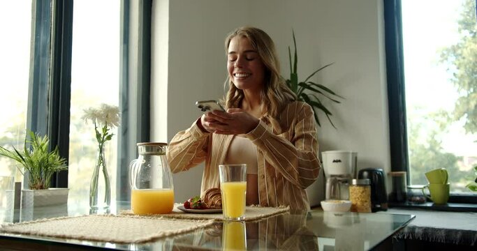 Cute smiling girl takes a picture of her breakfast on her phone