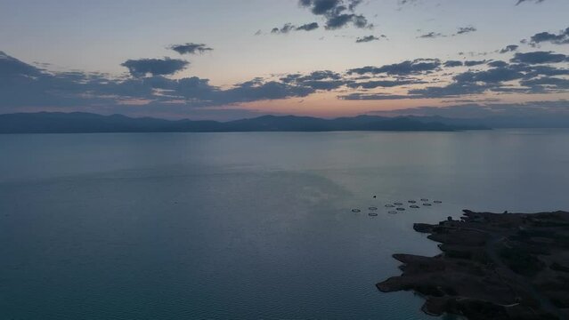 Scenic sunset or sunrise over Sevan lake popular holiday destination in Armenia, Caucasus, West Asia. Daytime Timelapse of moving white, grey clouds over lake Sevan on background hills