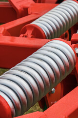 Steel silver spring as part of red agricultural machine. Technology