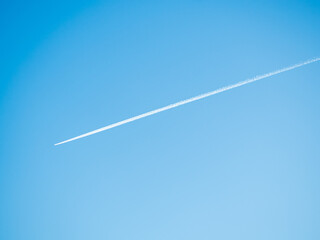 Estela blanca de un avion sobre cielo azul