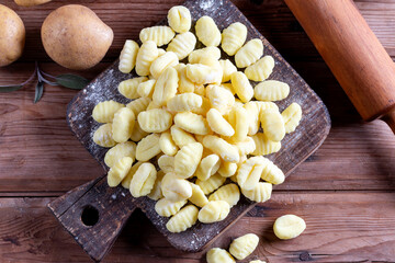 Wooden board with tasty gnocchi and spices on a wooden table. Top view