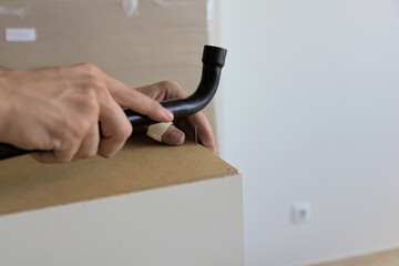 Hand assembly of new furniture by an individual using both specialized and homemade tools. Using furniture fittings during the assembly process.