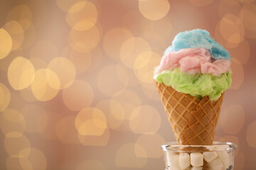 Sweet cotton candy in waffle cone against blurred lights, closeup. Space for text